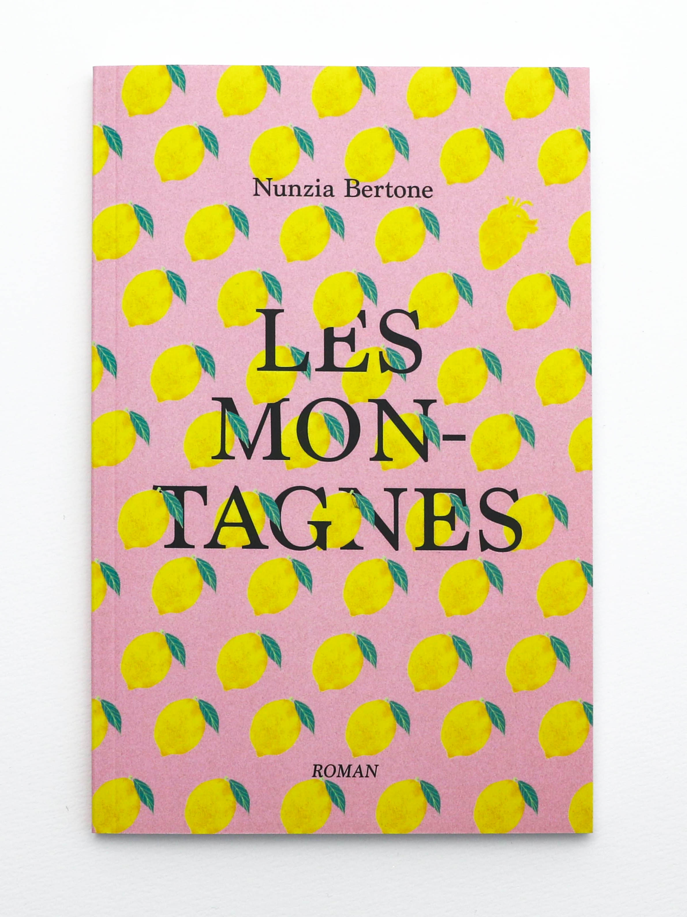 Première de couverture du roman Les Montagnes de Nunzia Bertone. Le titre est en lettres capitales. Une illustration de papier peint rose avec des citrons se mêle aux lettres. Parmis les citrons se chache un cœur.
